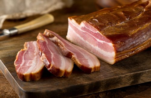 Delicious artisanal whole smoked slab bacon on a cutting block.